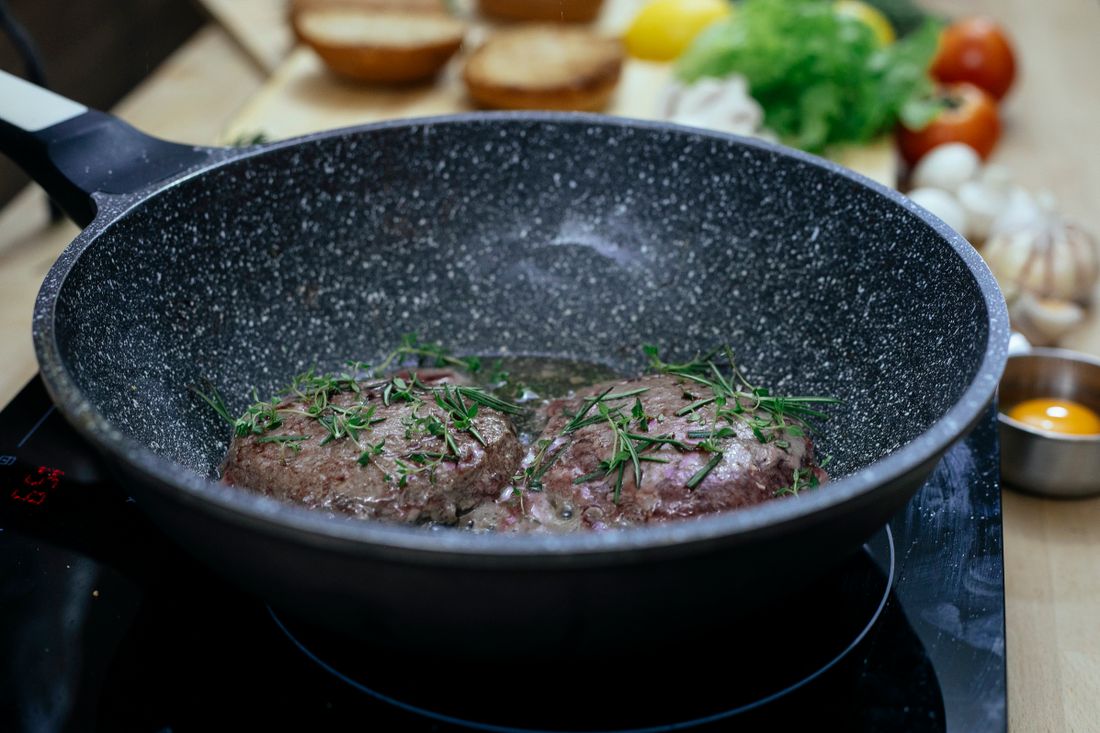 Beef burger patty cooking in a skillet