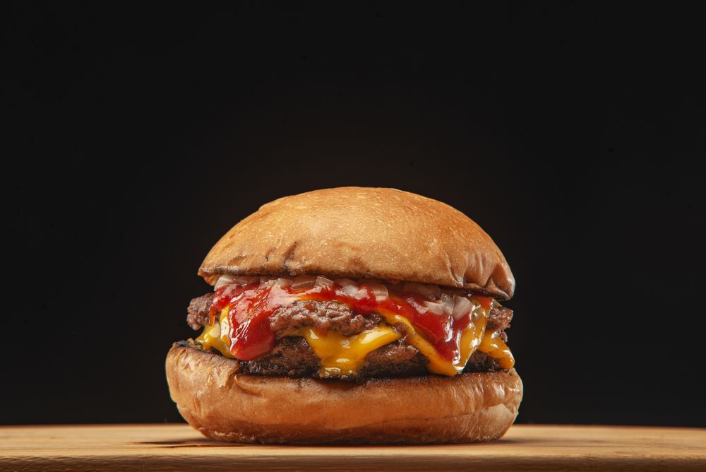 Cheeseburger with ketchup on dark plate